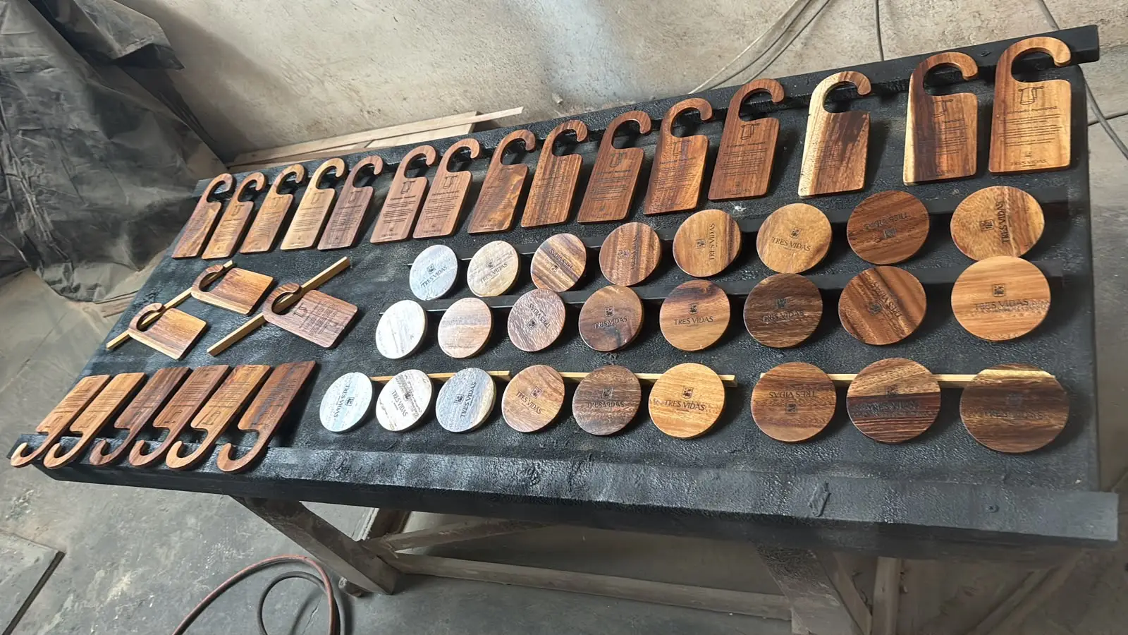 Lote de llaveros y fichas de madera grabadas dispuestos sobre una mesa negra
