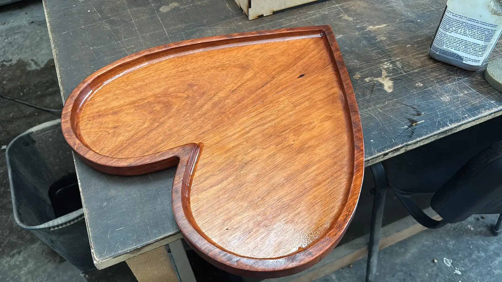 Charola de madera en forma de corazón barnizada sobre el banco de trabajo