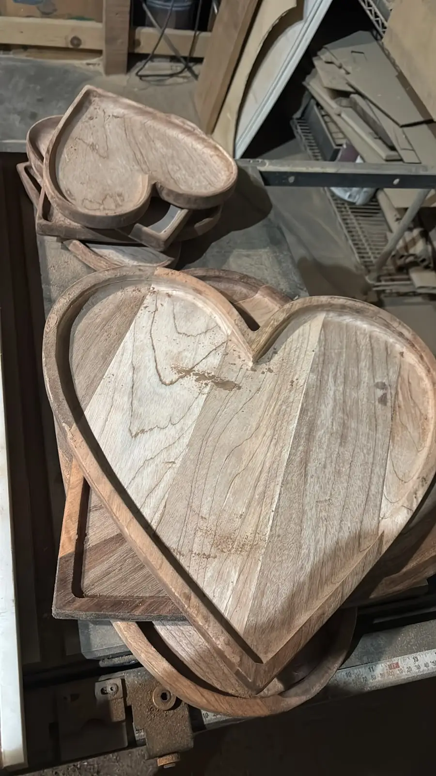 Charolas de madera en forma de corazón sin acabado, apiladas en el taller